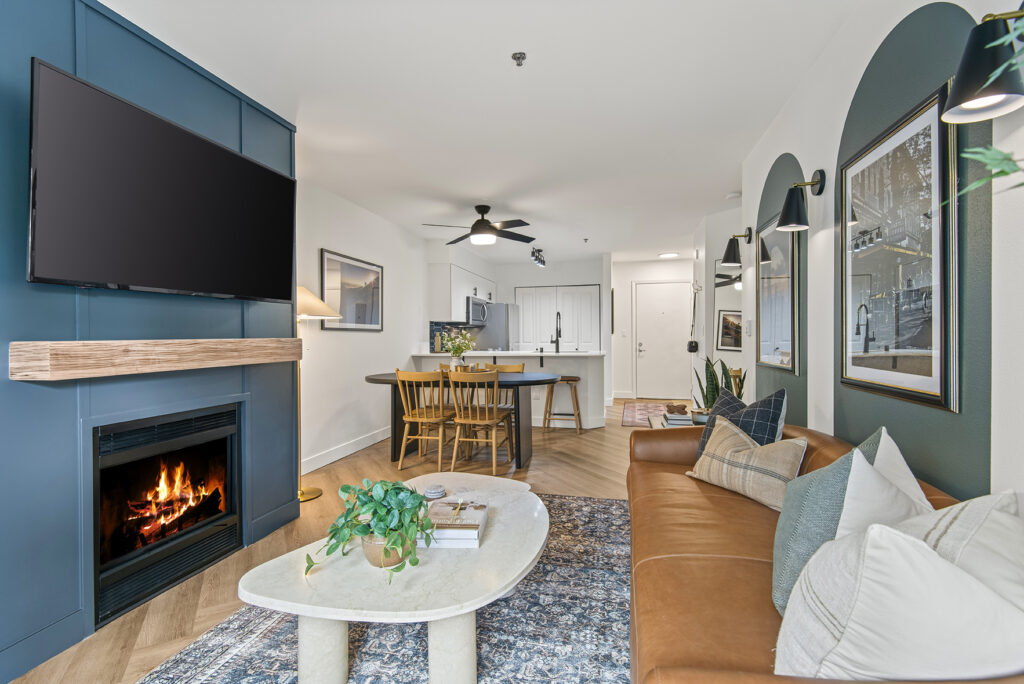 A modern living room with a fireplace and a flat screen TV mounted on the wall above in an apartment home